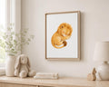 A framed watercolor art print of a sleeping golden lion displayed on a light beige wall above a wooden shelf styled with a bunny plush, books, a lamp, and a vase.