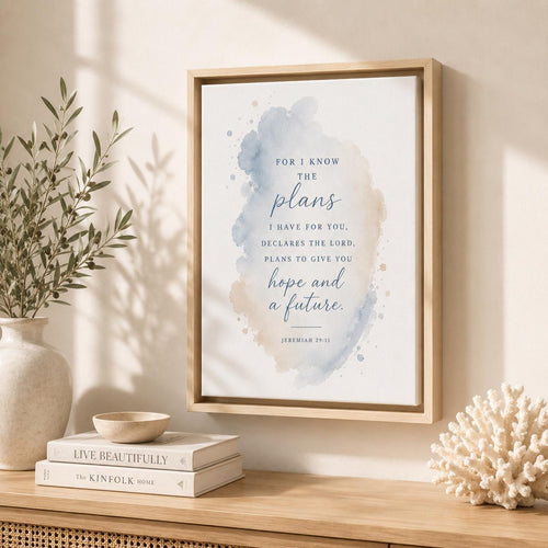 A framed inspirational Bible verse Jeremiah 29:11 print with a watercolor background, styled on a wooden shelf next to a vase with greenery and a book.