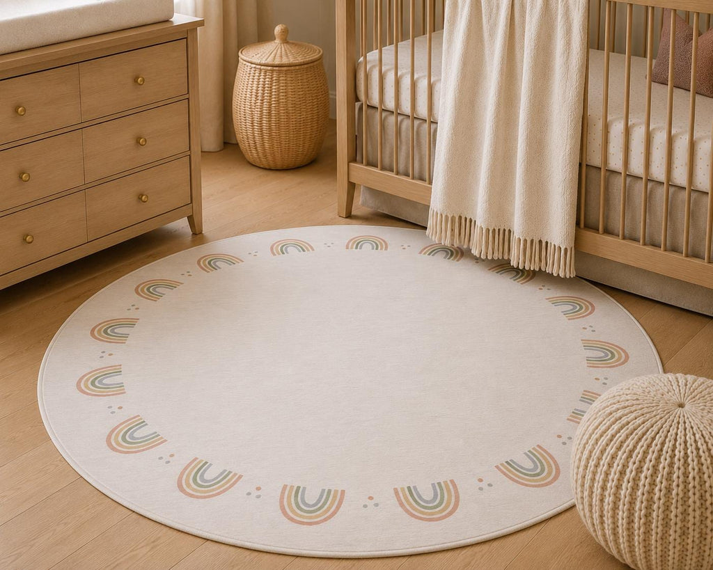 A round cream baby rug with a pastel rainbow border pattern, styled in a nursery next to a wooden crib and dresser.