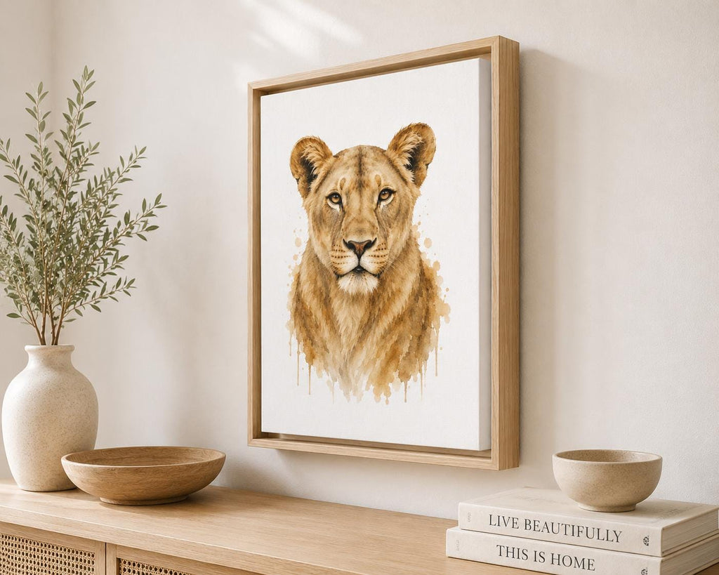 Framed watercolor-style lion print hanging on a light wall above a wooden console table, styled with a vase, bowls, and stacked books.