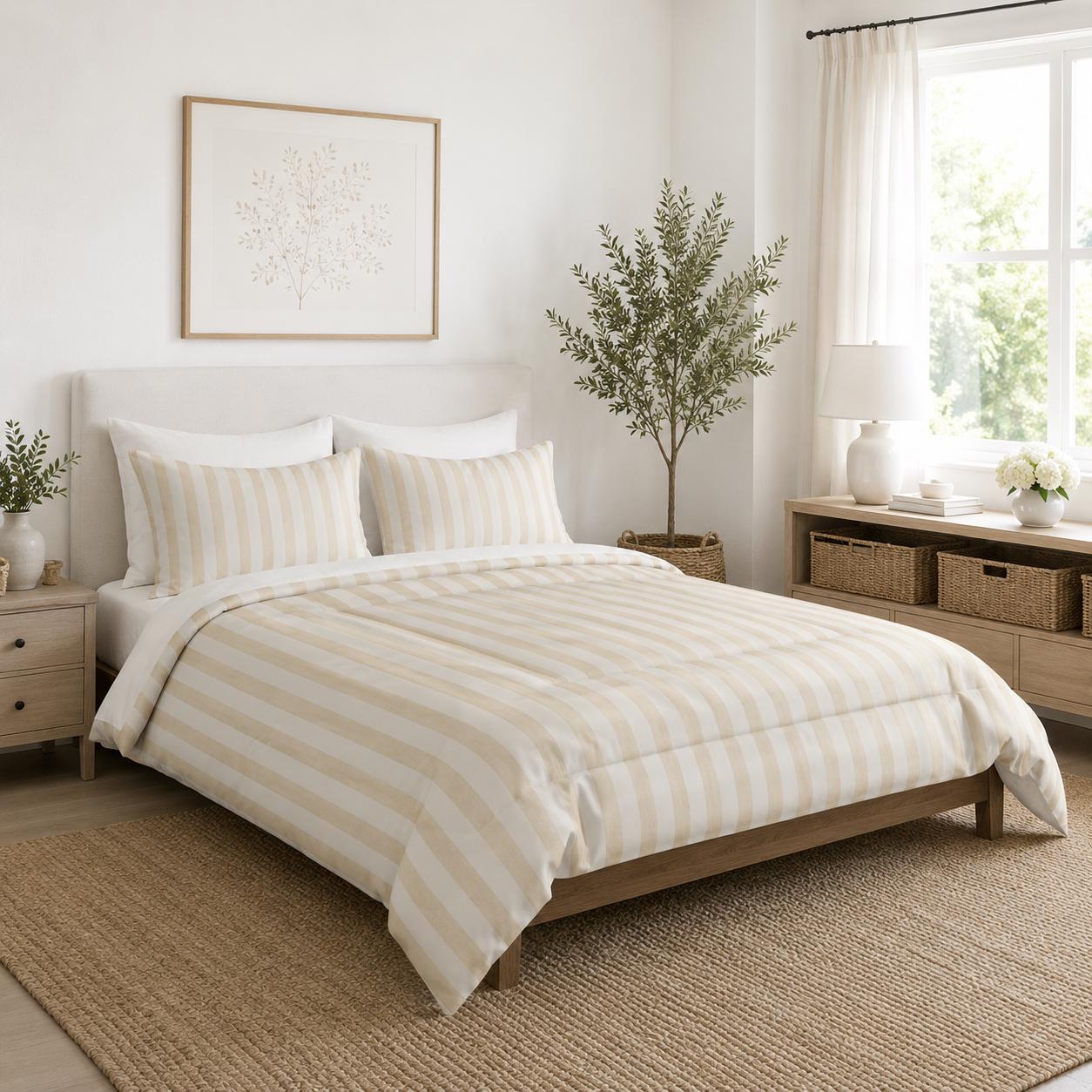 A neatly made bed in a bright, modern bedroom featuring a cream and beige striped duvet cover and matching pillow shams, set against a white wall with a wooden headboard.