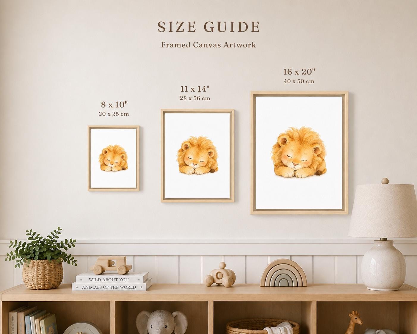 A size guide display for framed canvas artwork showing three framed lion prints in different sizes mounted on a wall above a shelf with decor items. The text reads 'SIZE GUIDE Framed Canvas Artwork' with dimensions labeled for each print.