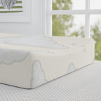 A fitted sheet with a soft gray cloud pattern on an off-white mattress, shown in a bright, modern bedroom setting next to a window.