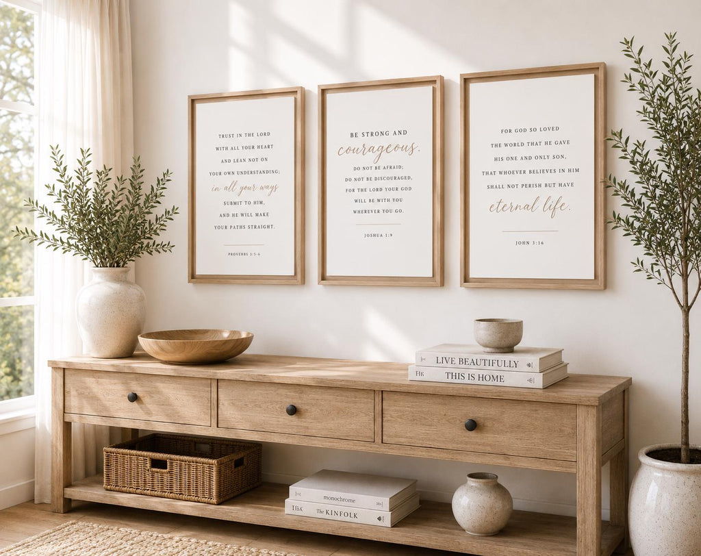 Three framed typography wall art prints with inspirational quotes hang above a light wood console table in a bright, styled room with plants and decor.
