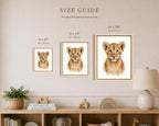 A size guide poster showing three framed canvas prints of lion cub portraits in different sizes (8 x 10, 11 x 14, and 16 x 20 inches) mounted on a beige wall above a wooden shelf with home decor.