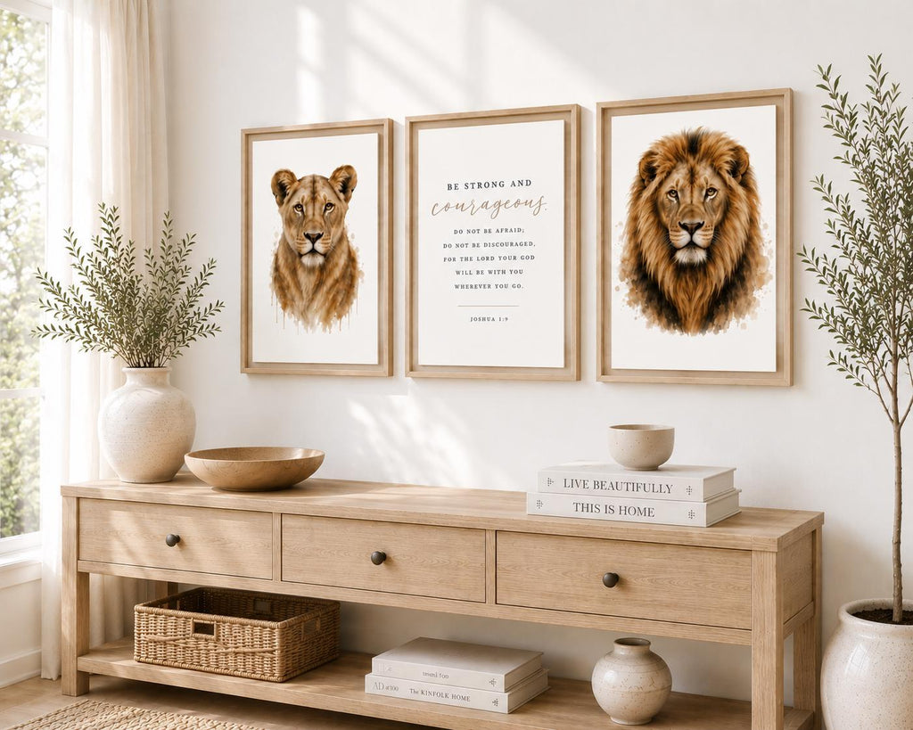 Three framed wall art prints hang above a light wood console table in a bright, styled room. The left print shows a lion cub, the center print features an inspirational quote, and the right print shows a lion.