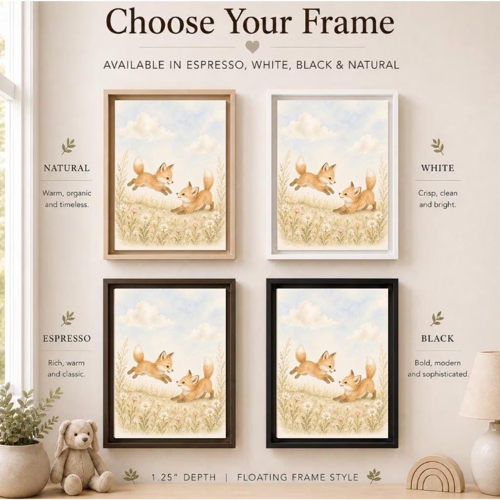 A framed art print set displayed in four color options (Natural, White, Espresso, Black) on a beige wall. The prints feature a watercolor illustration of two playful foxes in a grassy field under a soft blue sky.