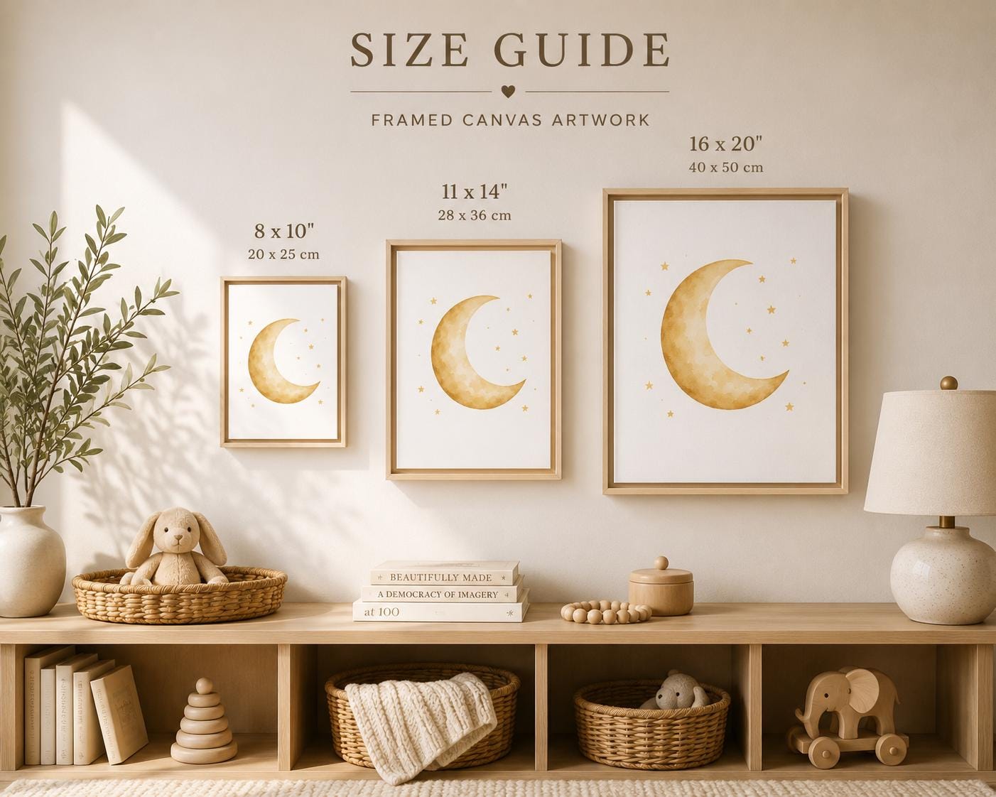 A styled nursery wall with three framed canvas prints showing crescent moon artwork, labeled with sizes 8 x 10", 11 x 14", and 16 x 20". The scene includes a wooden shelf with books, baskets, a lamp, and a bunny toy, under the heading 'SIZE GUIDE' for framed canvas artwork.