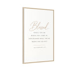 A vertical framed wall art print with a white background and a thin light wood frame. The print features the word 'Blessed' in elegant cursive, followed by the biblical quote 'Shall you be when you come in, and blessed shall you be when you go out' from Deuteronomy 28:6-7 in dark gray serif text.