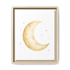Framed wall art featuring a watercolor-style crescent moon and small stars in warm beige and gold tones on a white background, shown in a light wood frame against a white wall.