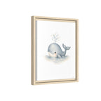 Framed wall art featuring a cute gray baby whale blowing bubbles on a white background, housed in a light natural wood frame.