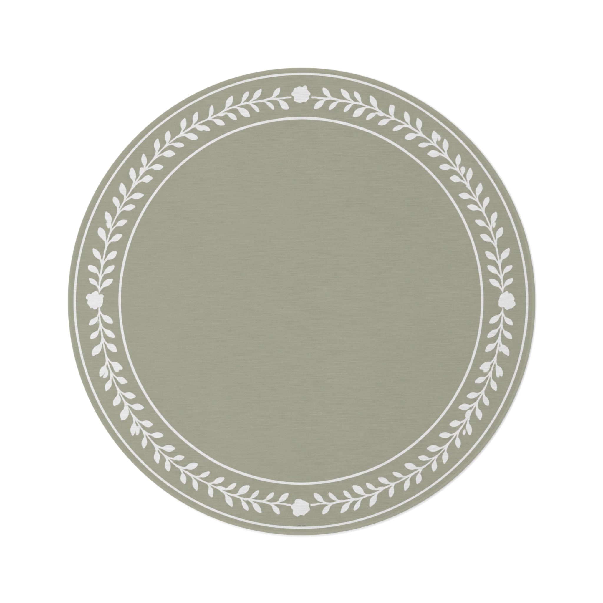 A round area rug in sage green with a white leafy floral border, styled on a white background