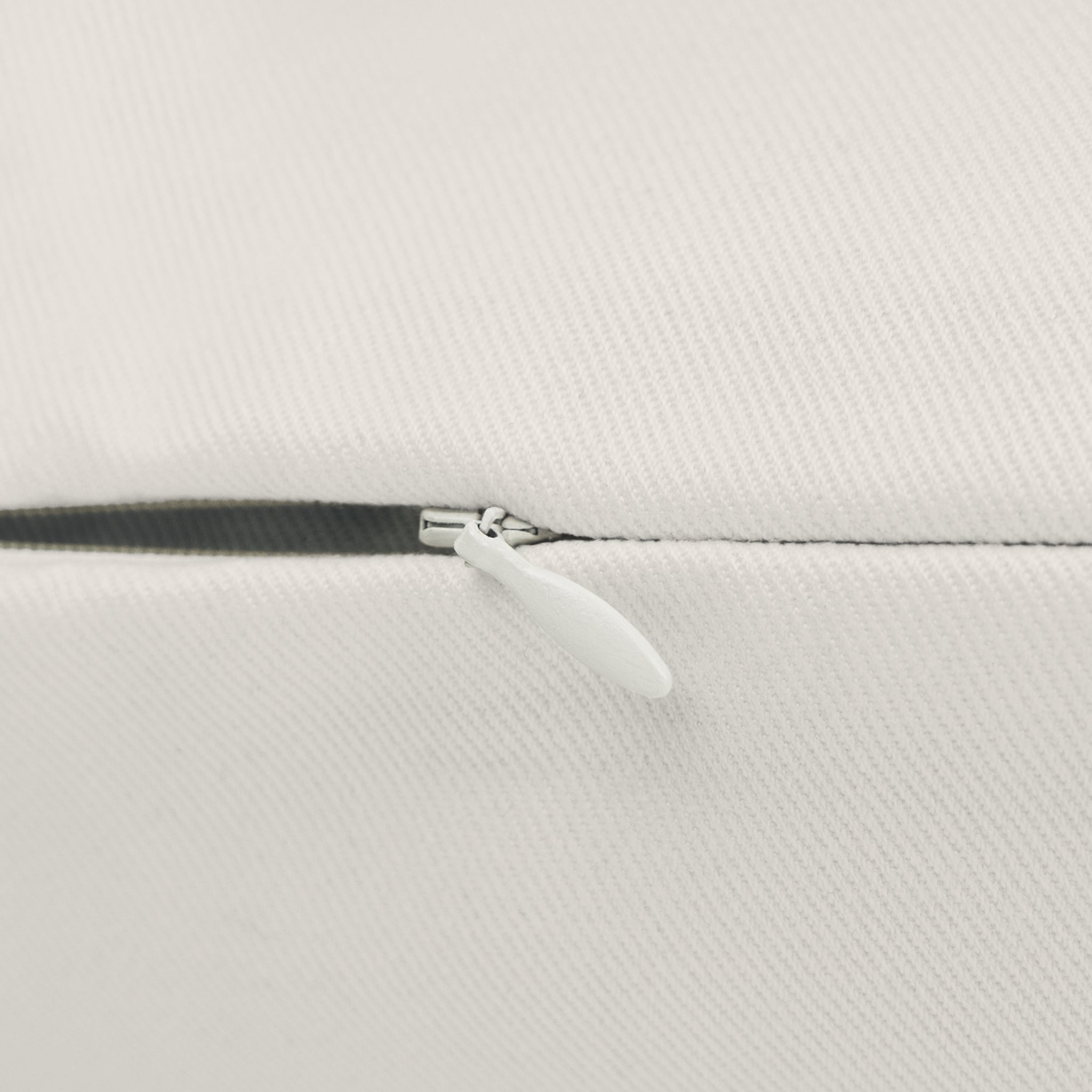Close-up of a white textured fabric surface with a black zipper and a white pull tab.