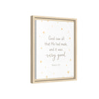 A framed wall art print with a light wood frame, featuring the quote 'God saw all that He had made, and it was very good. Genesis 1:31' in gray text on a white background with scattered small gold stars.