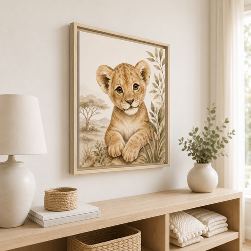 A framed art print of a cute safari lion cub illustration hanging on a warm beige wall above a light wood console table with a lamp, basket, and plant.