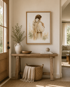A framed art print depicting a man Jesus in a cream-colored cloak carrying a white lamb, styled on a wooden console table with a vase, bowl, and books in a warm, neutral-toned room.