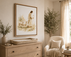 A floating Canvas in a wooden natural frame artwork showing a man, Jesus, in white robes being a Shepherd leading two lamb behind him while holding a Shepherd's staff in a watercolor green floral field. It is styled above a dresser with a vase, a basket, with an olive tree and cream colored chair in the corner. The colors are very cream and neutral.