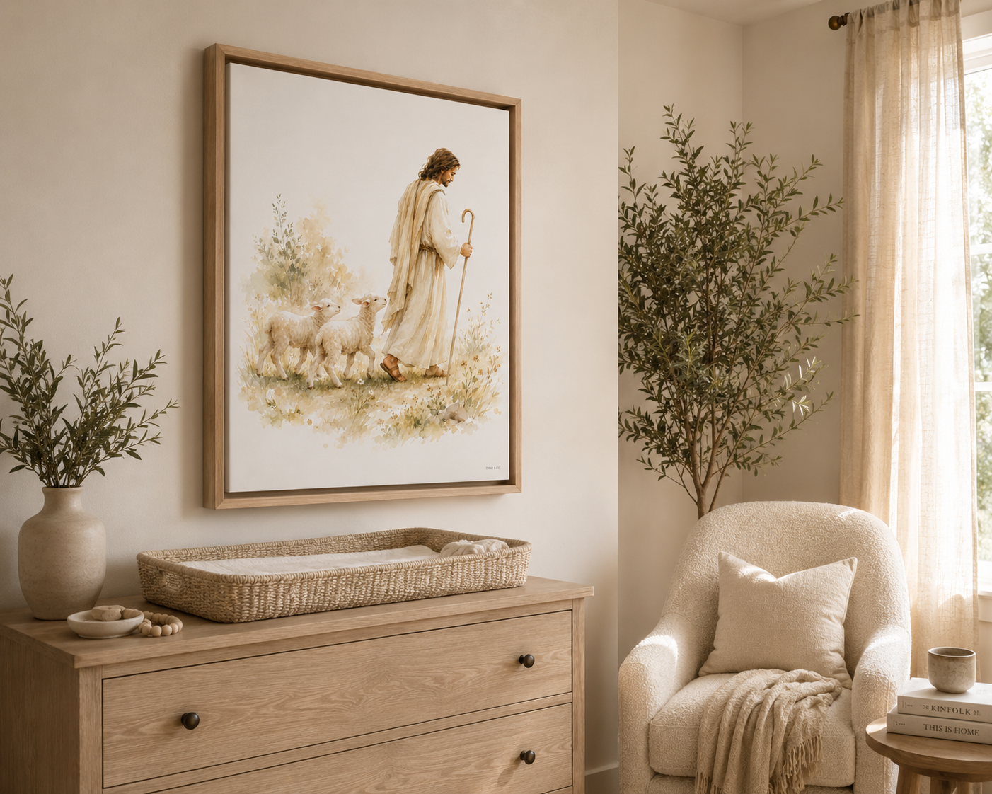 A floating Canvas in a wooden natural frame artwork showing a man, Jesus, in white robes being a Shepherd leading two lamb behind him while holding a Shepherd's staff in a watercolor green floral field. It is styled above a dresser with a vase, a basket, with an olive tree and cream colored chair in the corner. The colors are very cream and neutral.