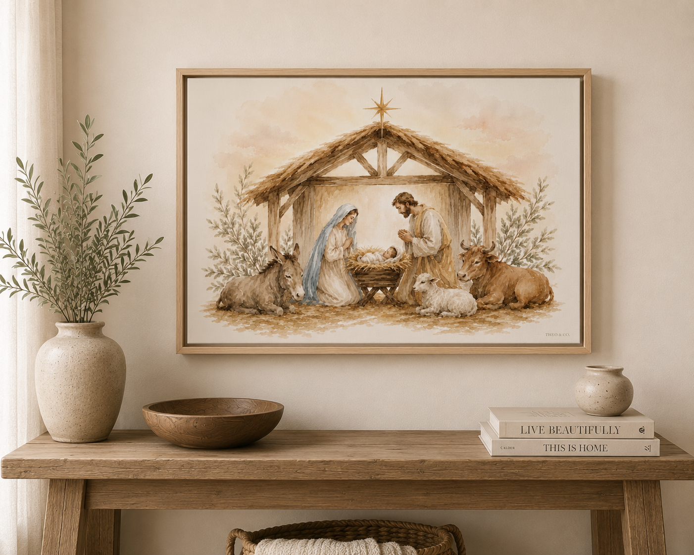 A framed art print depicting a rustic nativity scene hangs on a beige wall above a wooden console table styled with a vase, bowl, and books.