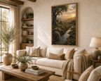 A framed landscape painting of a sunlit forest stream hangs on a beige wall above a cream sofa in a styled living room with shelves, a coffee table, and a lamp.