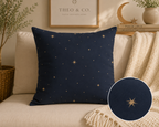 A navy blue throw pillow with a gold star pattern, styled on a beige sofa with a cream knit blanket and a circular fabric detail inset.