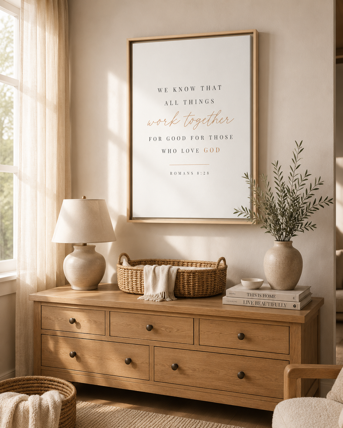 A framed wall art print with a Bible verse in black and rose-gold typography, displayed in a warm, styled room above a wooden dresser with a lamp, basket, and books.