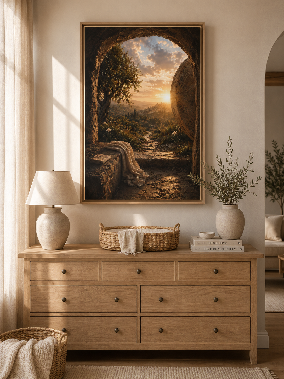 A framed landscape art print depicting a sunset over a river canyon, styled on a beige wall above a light wood dresser in a warm, modern room.