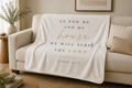 A cream-colored fleece throw blanket draped over a beige sofa in a styled living room. The blanket features the printed text 'AS FOR ME AND MY house WE WILL SERVE THE LORD JOSHUA 24:15' in dark gray and rose gold lettering.
