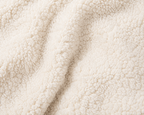 Close-up of a soft, plush sherpa fabric in a warm off-white or cream color, showing the textured pile and gentle folds.