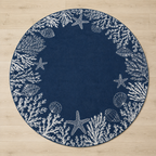 A round navy blue rug with a white seashore pattern featuring starfish, shells, and coral, laid flat on a light wood floor.