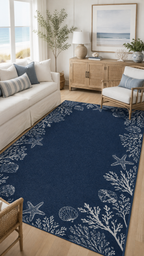 A navy blue area rug with a white ocean-themed border featuring starfish, seashells, and coral, shown in a bright, modern living room setting.