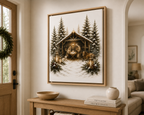 A framed Christmas nativity scene print hangs on a beige wall above a wooden console table in a styled home interior. The artwork shows a snowy stable with pine trees, warm lantern light, and figures in a rustic scene.