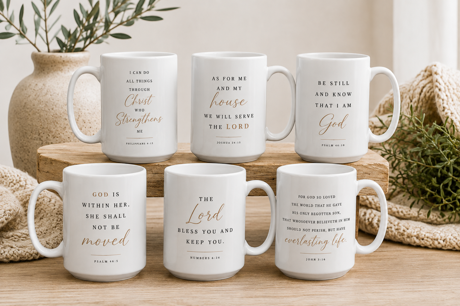 Six white ceramic mugs with gold and black Bible verses, arranged on a wooden block with a neutral background and decorative plants.