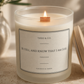 A lit jar candle with a wooden wick and cream-colored wax in a frosted glass container. The front label reads 'THEO & CO.