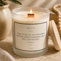 A lit scented candle in a frosted glass jar with a wooden wick, labeled 'THEO & CO.' and featuring a Bible verse from Matthew 2:28.
