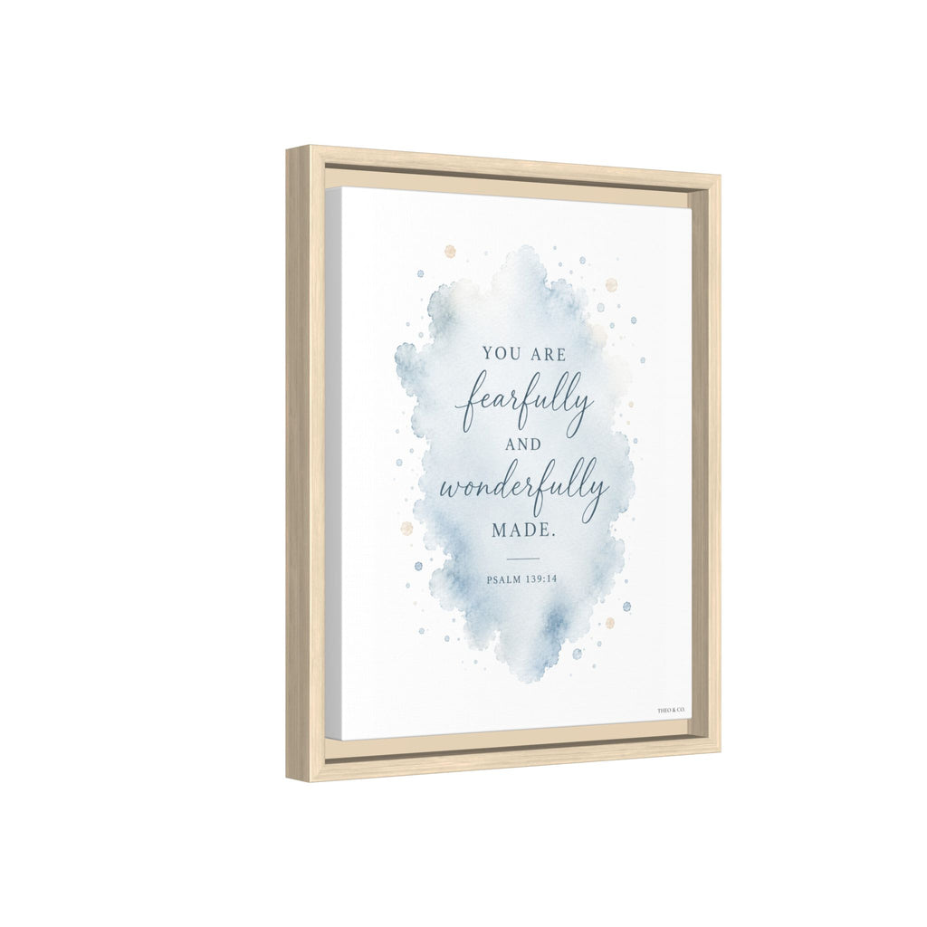 Framed wall art print with a watercolor blue splash and the quote 'YOU ARE fearfully and wonderfully MADE.' on a white background, shown in a light natural wood frame against a white backdrop.