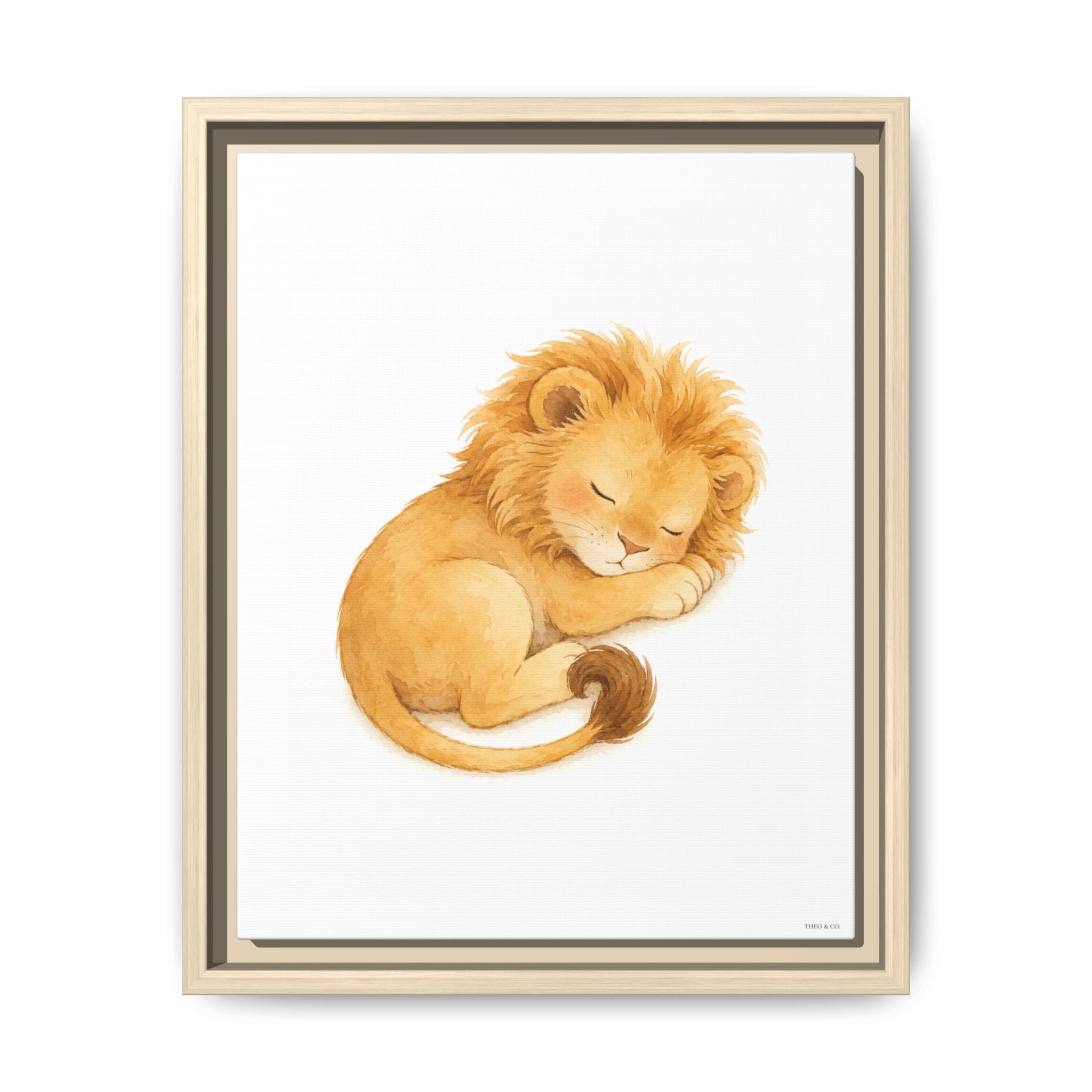 Framed wall art featuring a watercolor illustration of a sleeping lion cub in warm golden and tan tones on a white background, shown in a light wood frame against a white wall.