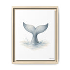 A framed art print featuring a watercolor illustration of a whale tail fin rising from the ocean, presented in a light natural wood frame against a clean white background.
