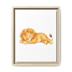 Framed wall art featuring a watercolor illustration of a sleeping lion cub in warm golden and tan tones on a white background, shown in a light wood frame against a white wall.
