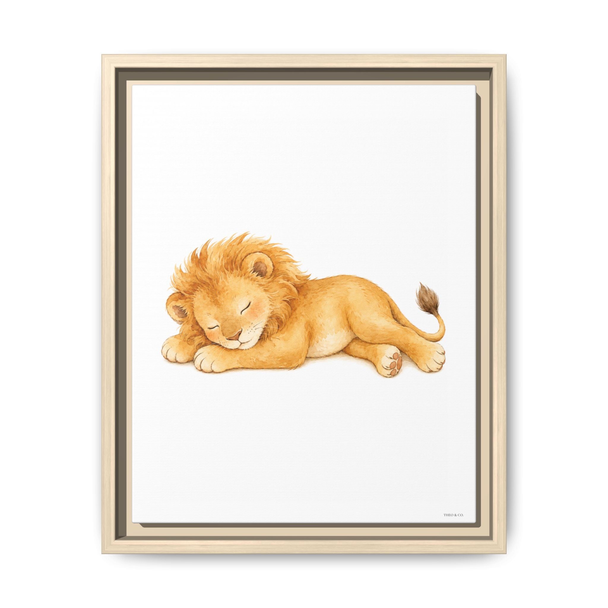 Framed wall art featuring a watercolor illustration of a sleeping lion cub in warm golden and tan tones on a white background, shown in a light wood frame against a white wall.