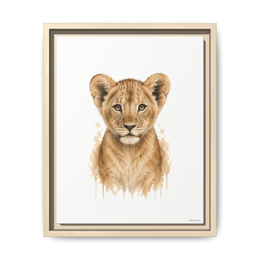 A framed watercolor-style art print featuring a lion cub centered on a white background, with a light wood frame and dark inner trim, shown against a plain white wall.