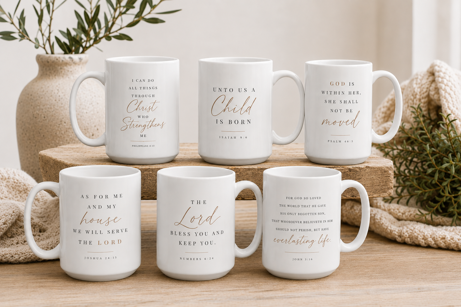 Six white ceramic mugs with gold and black Bible verse quotes, arranged on wooden blocks and a light wood surface with neutral home decor props.