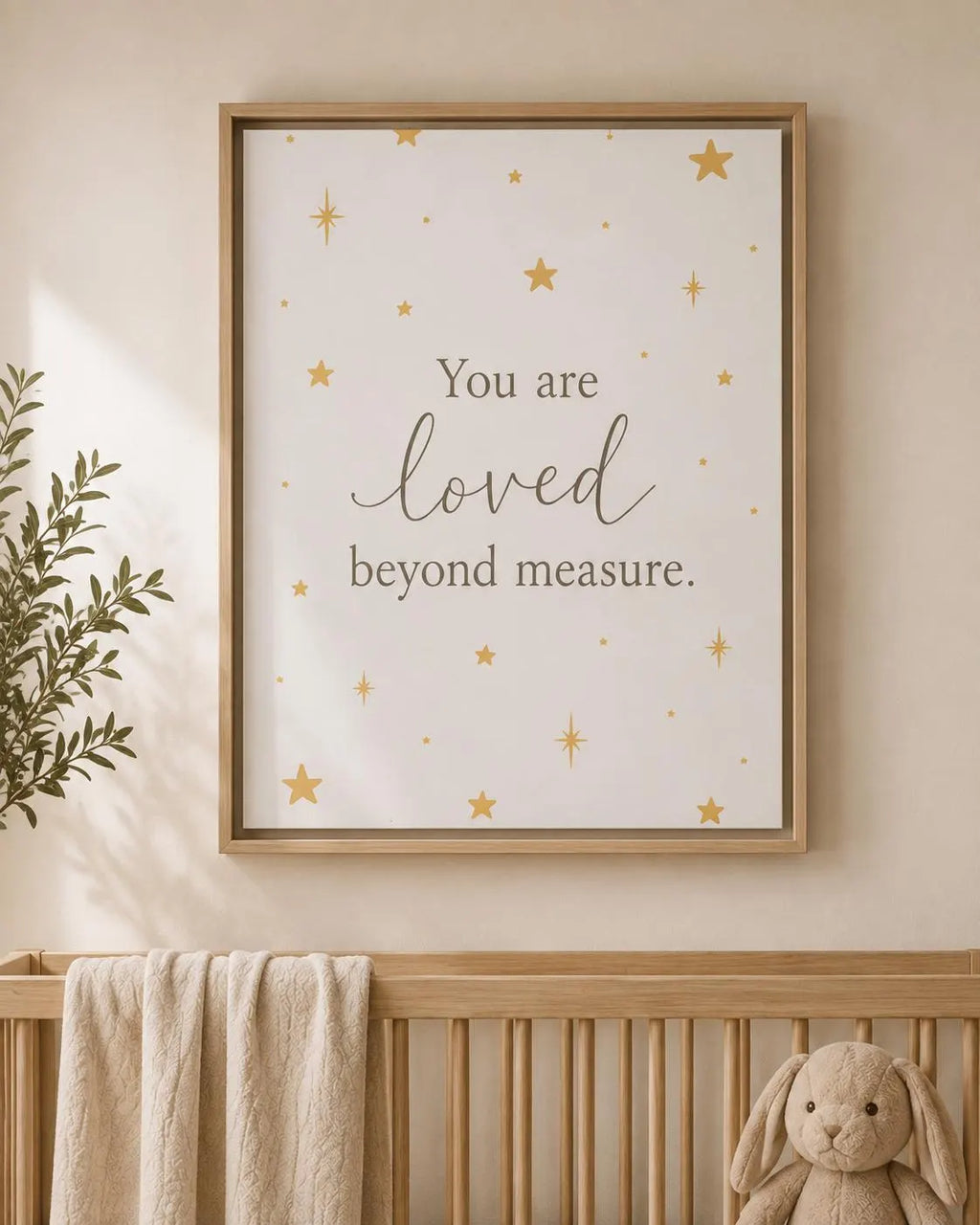 A framed nursery wall art print with the phrase 'You are loved beyond measure.' in dark gray script and serif text, decorated with small gold stars on a warm off-white background.