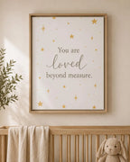 A framed nursery wall art print with the phrase 'You are loved beyond measure.' in dark gray script and serif text, decorated with small gold stars on a warm off-white background.